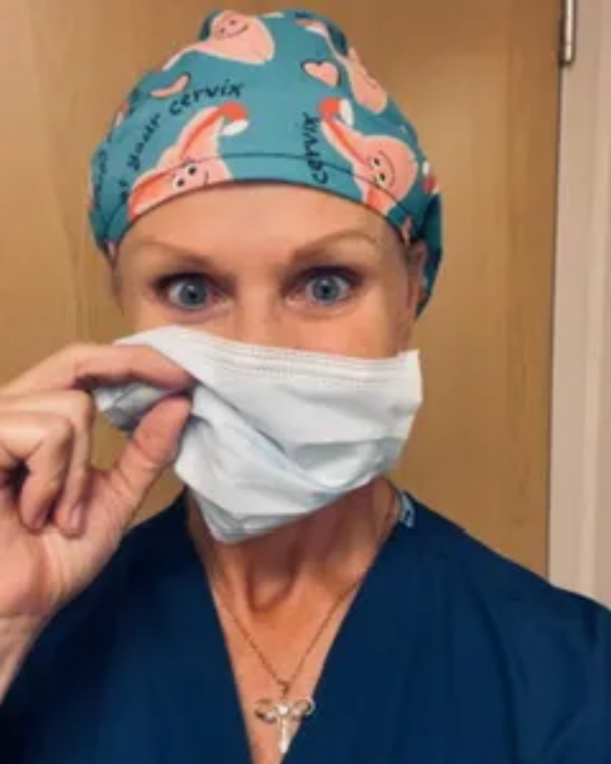 A woman wearing surgical masks and a scrub hat.
